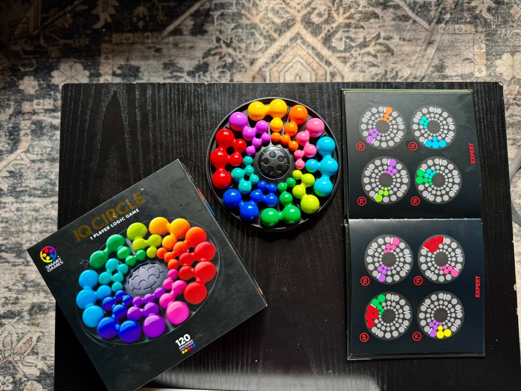 Overhead view of the IQ Circle game, challenge booklet and colorful completed board