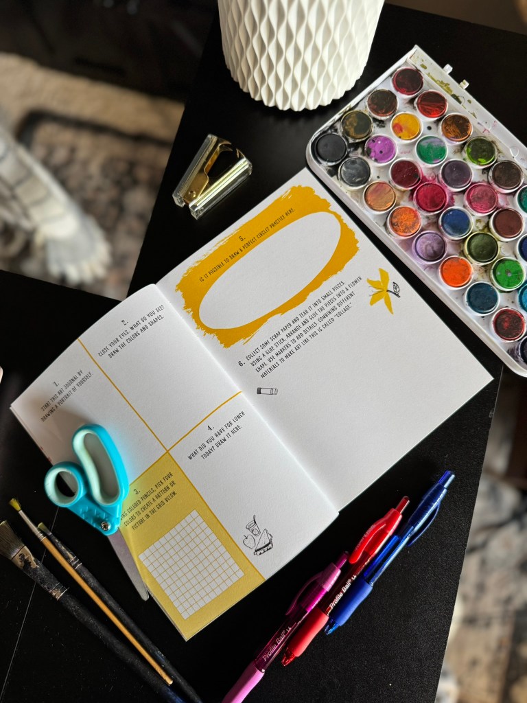 An open art book lies on a table, featuring colorful watercolor paints, scissors, pens, and a stapler, with worksheet prompts encouraging creative exploration.