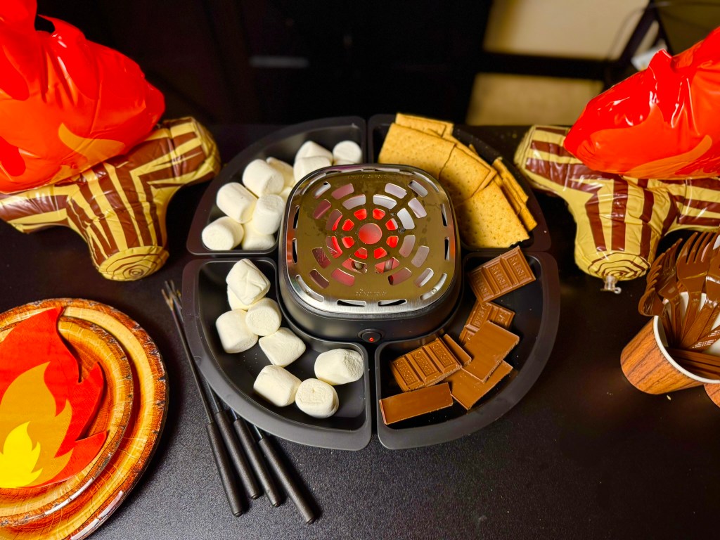 Camping party food idea with s’mores tray, marshmallows, chocolate bars, and graham crackers.