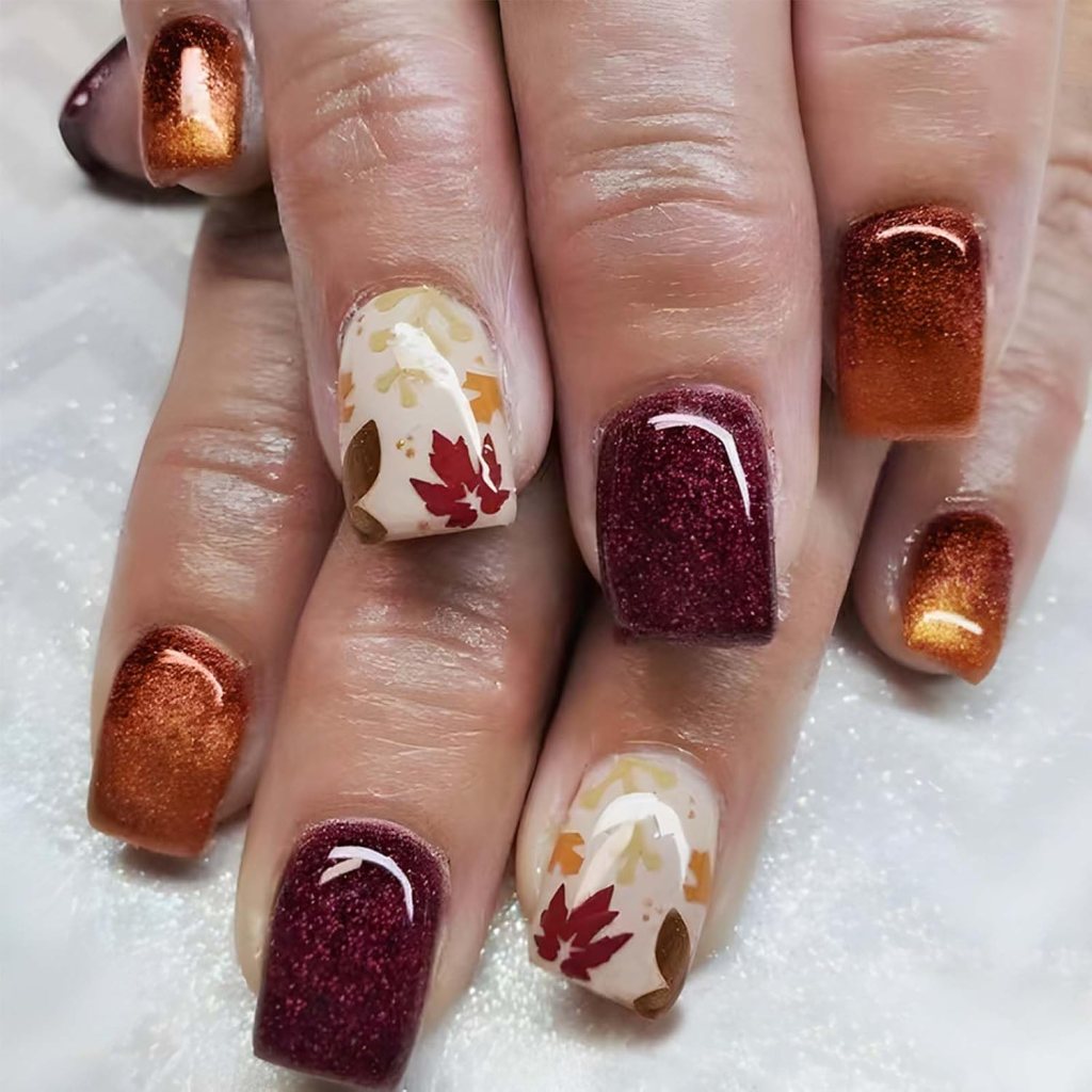 Autumn-inspired nails featuring a mix of burnt orange, burgundy, and shimmering gold, with delicate leaf designs on a neutral base for a festive Thanksgiving look.