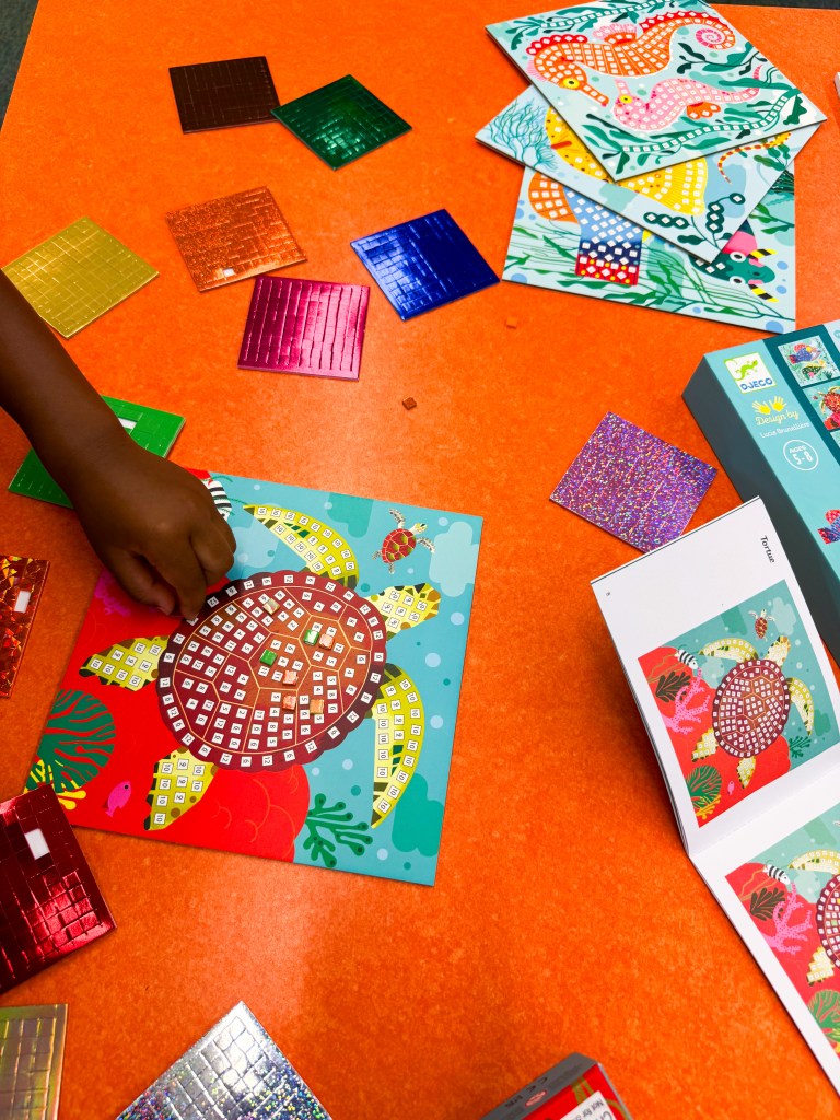 Kindergartner placing numbered mosaic pieces onto a turtle board using the visual guide.