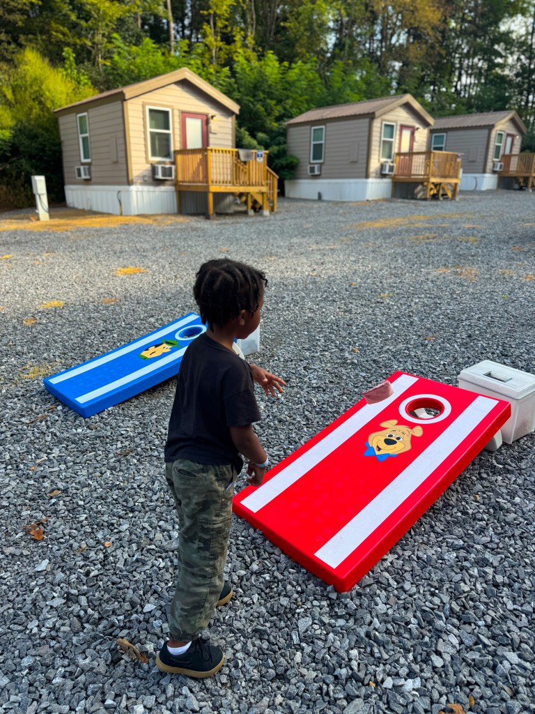 Child playing cornhole near the cabins at Jellystone Park Pigeon Forge